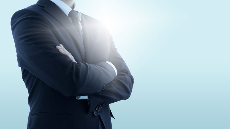 自信に満ちた様子で腕組みをするスーツ姿の男性