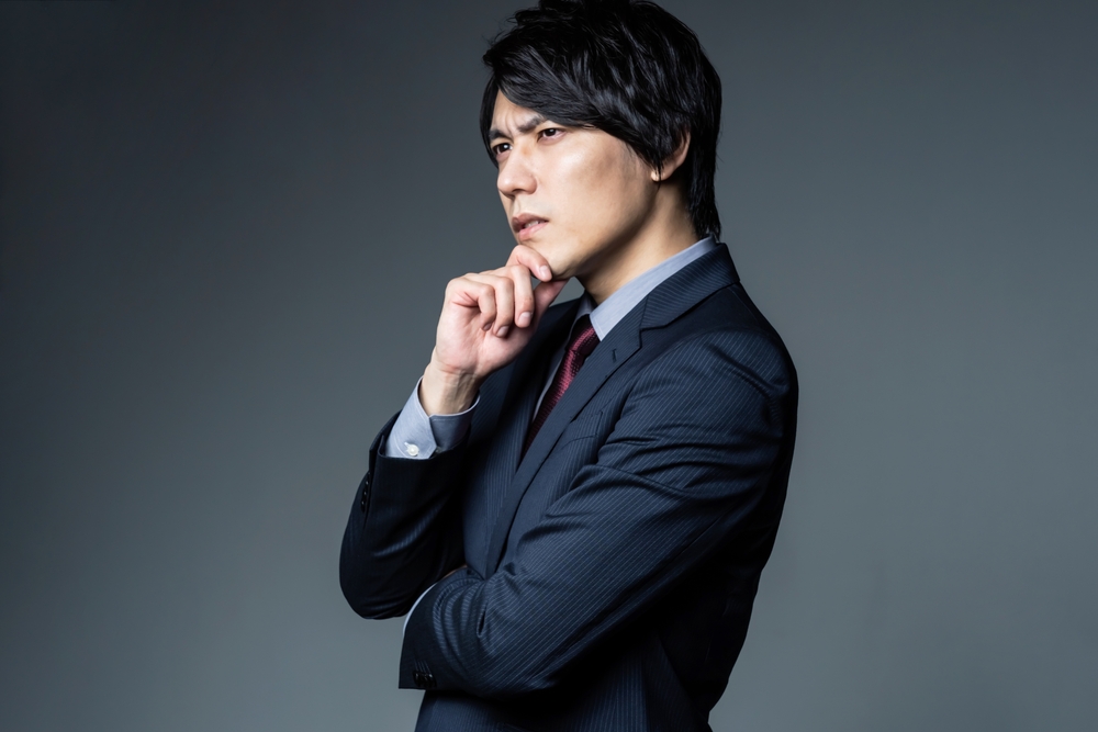 会社経営のデメリットや潜在的リスクを冷静に分析するスーツ姿の男性