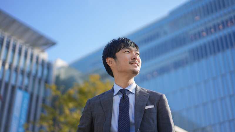 経営者を目指すビジネスパーソンがビル街を見渡しているイメージ