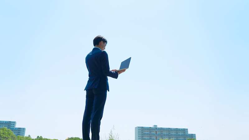 自然の中でノートパソコンを広げるビジネスマン