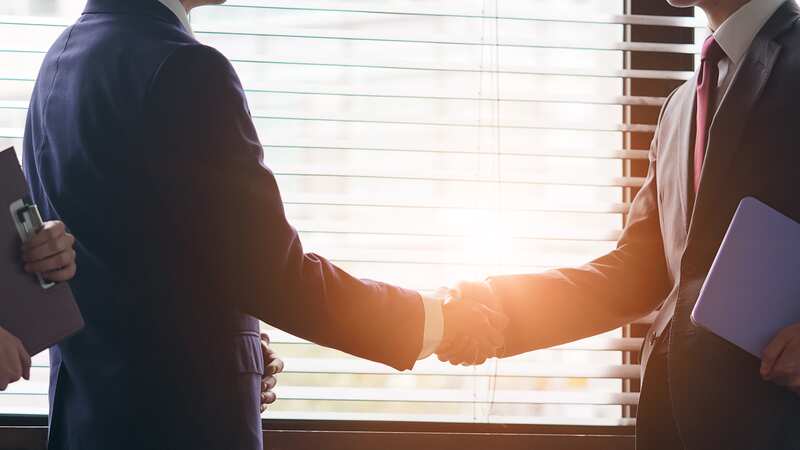 地方企業の事業承継交渉を終えて握手を交わす経営者と後継者のイメージ