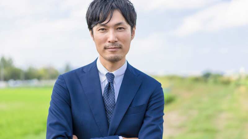 田舎での起業を目指し自然の中で力強く立つビジネスマンのイメージ